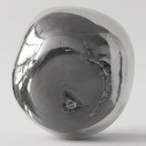 Chrome glass wall sconce with an irregular rounded shade and mirrorlike reflections against a light gray background.