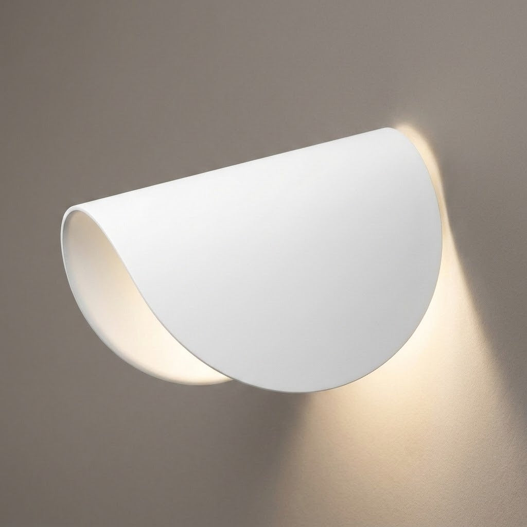 A modern semi-circular wall sconce light fixture in matte white, shown mounted on a neutral gray wall with warm light glowing from within.