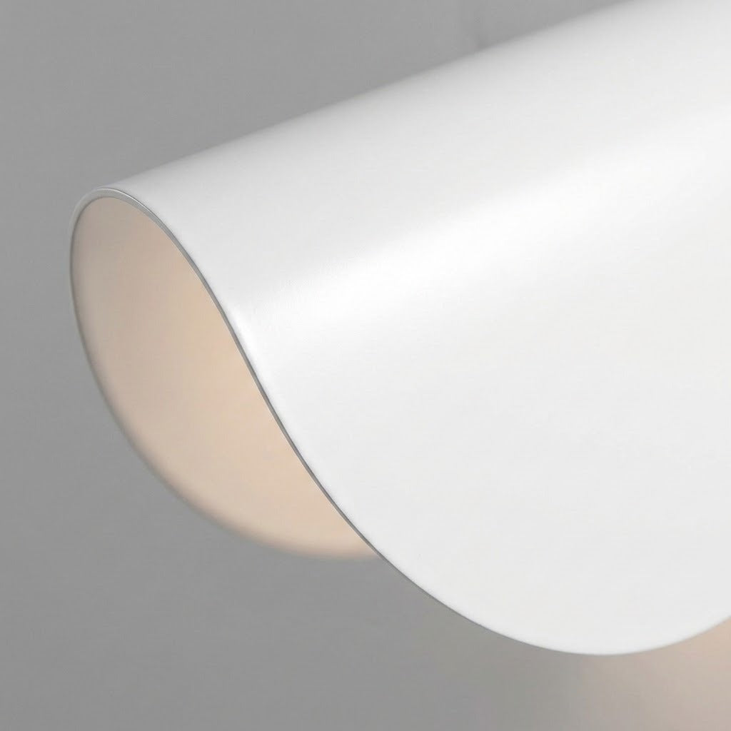 A close-up of a white wall sconce shows its smooth curved shade and softly illuminated inner surface against a gray background.