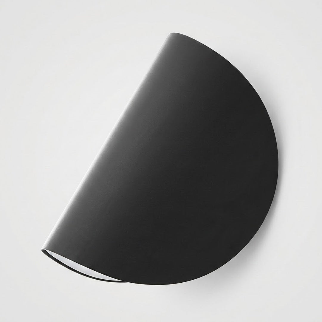 A minimalist black semi-circular wall sconce with a matte finish, shown mounted on a clean white wall.