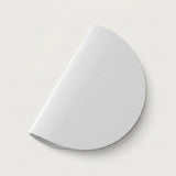 A white wall sconce with a smooth semicircular shade sits diagonally against a light background with a soft shadow.
