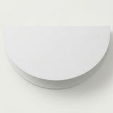 A white wall sconce with a semicircular shade and curved lower housing appears against a plain light background.