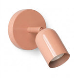 A glossy pink wall sconce with a round mounting plate and adjustable cylindrical shade on a plain white background.