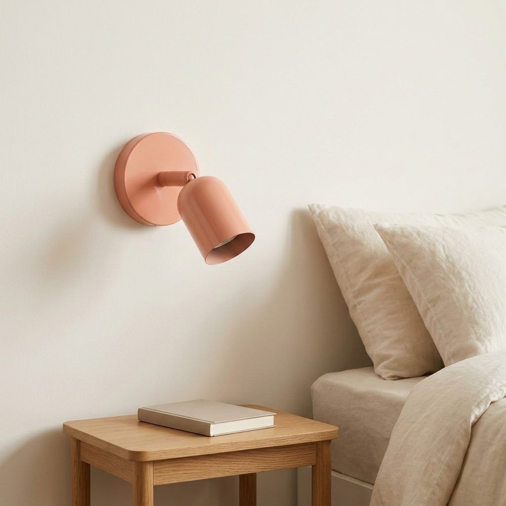 A peach pink wall sconce on a cream wall above a wooden nightstand, beside a beige sofa with soft cushions.