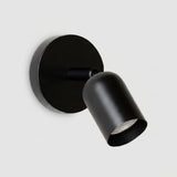 A modern matte black spotlight wall sconce with a circular backplate and adjustable cylindrical shade, shown against a light gray background.