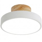 A modern flush-mount ceiling light featuring a wide white circular shade and a natural light-wood ceiling mount, shown against a plain white background.