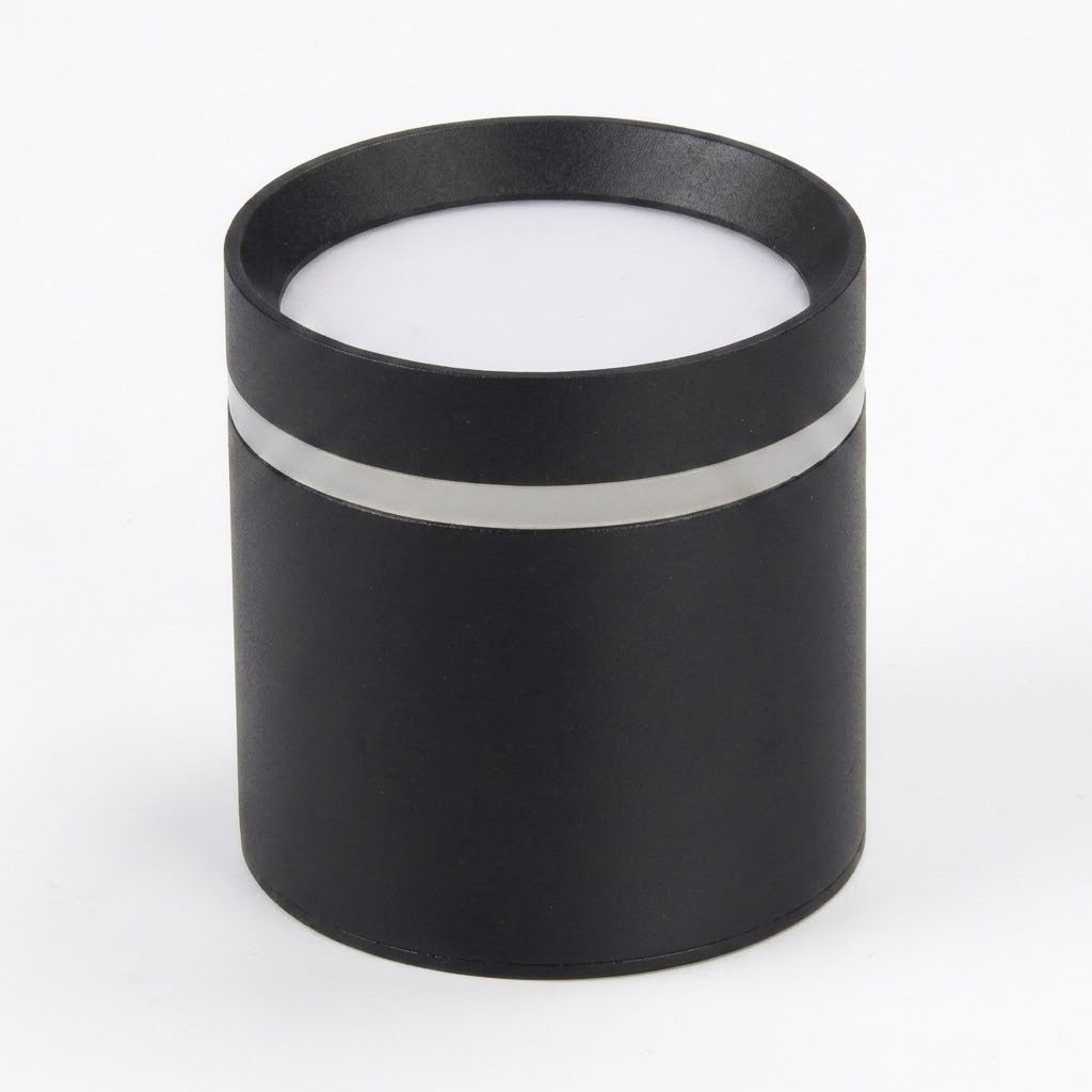 Black cylindrical LED downlight rests diffuser-side up on a white background, showing its silver-colored band and circular white diffuser.