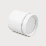 A white cylindrical LED downlight lies angled on a light gray background, showing its circular diffuser and silver-colored accent ring.