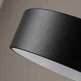 Close-up of a black pendant light’s textured painted metal shade and white interior against a neutral background.
