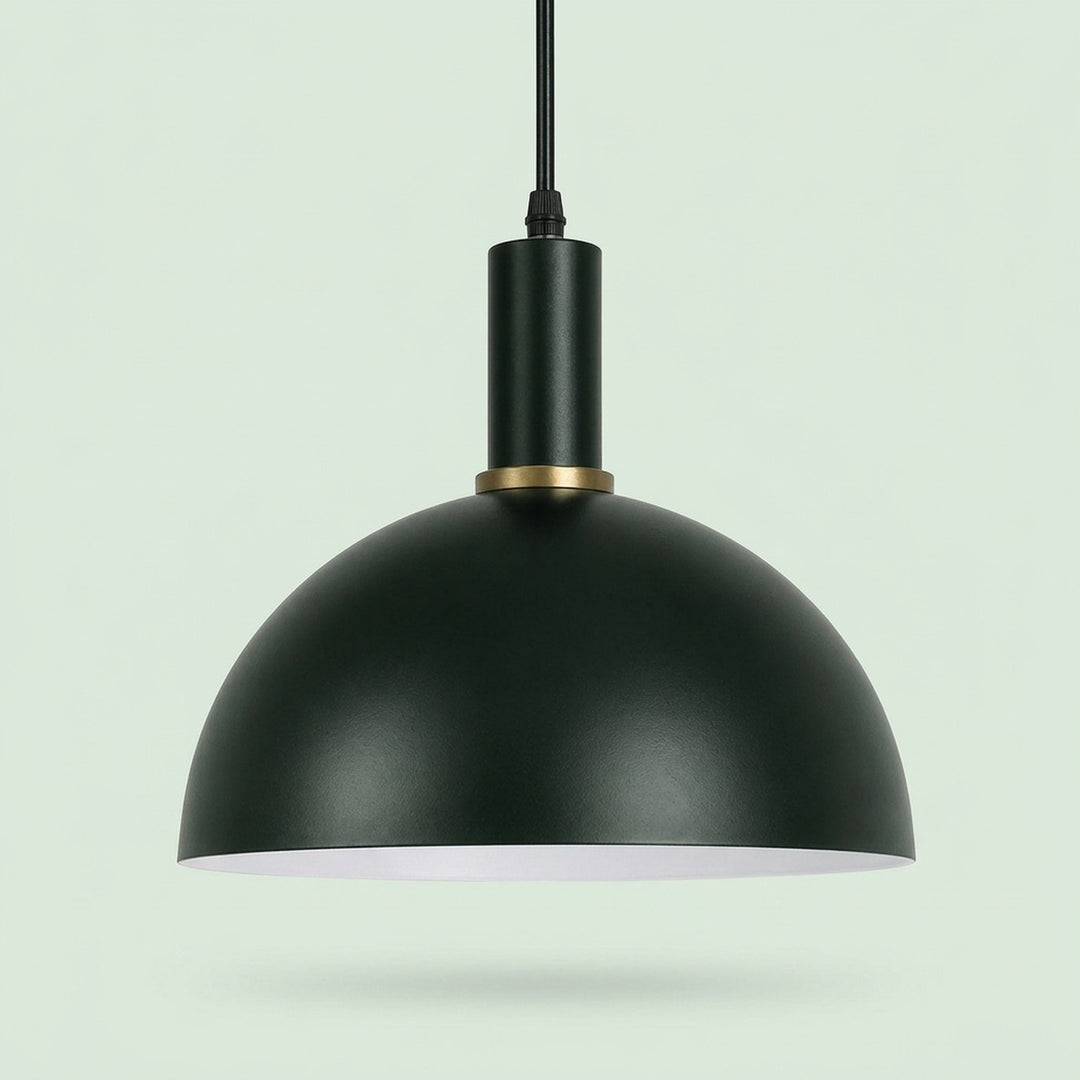 A matte black dome pendant light with a gold accent ring and a white interior, suspended against a pale green background.