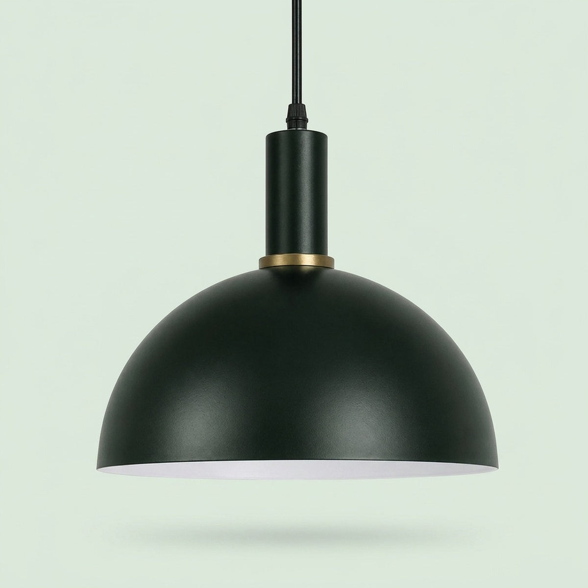 A matte black dome pendant light with a gold accent ring and a white interior, suspended against a pale green background.