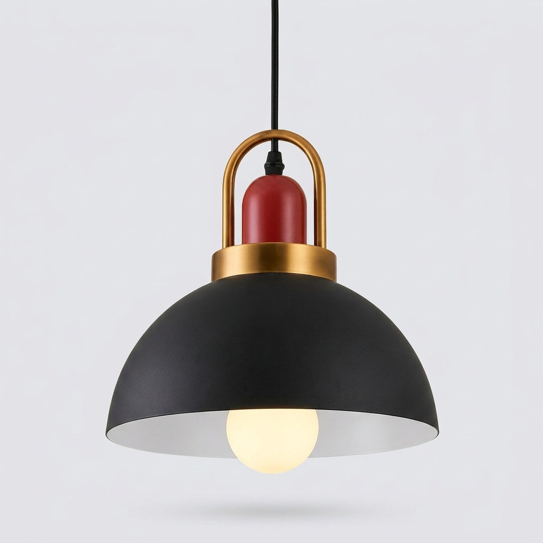 A modern pendant light with a matte black dome shade, a warm gold metal top frame, a red cylindrical accent, and a glowing light bulb inside, shown against a light gray background.