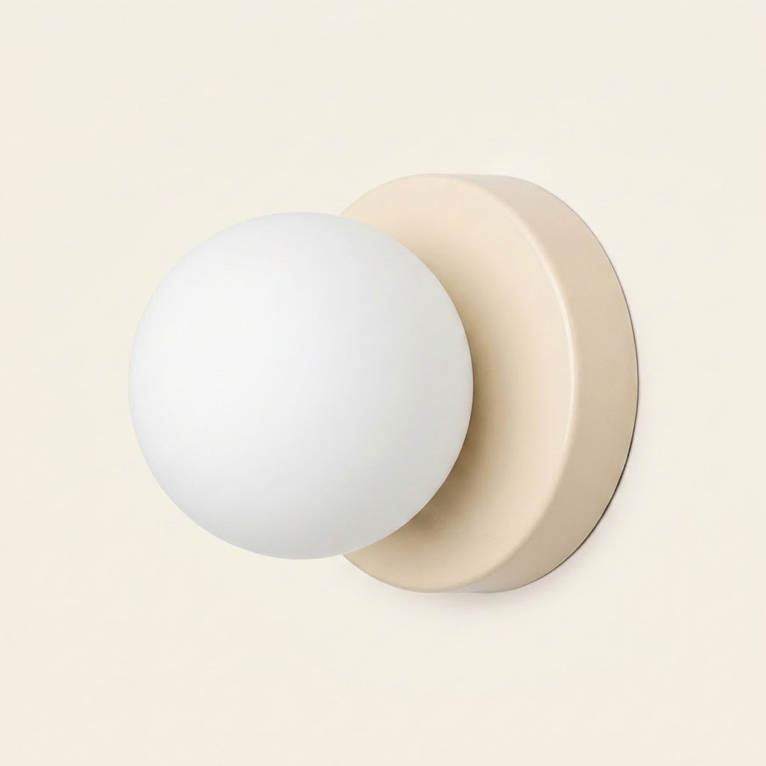 Wall sconce with a white plastic globe shade and beige circular iron base shown against a plain cream background.
