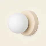 Wall sconce with a white plastic globe shade and beige circular iron base shown against a plain cream background.