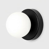 Wall sconce with a white plastic globe shade and black circular iron base against a light gray background.