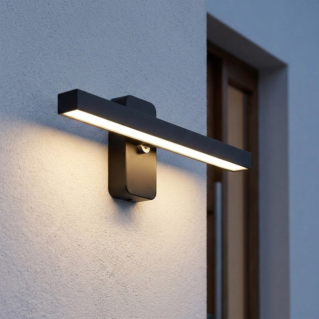 Dark wall sconce with a slim horizontal light bar casts warm white light onto textured stucco beside an exterior doorway.