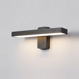 A modern horizontal wall sconce light fixture in a matte dark gray finish, mounted on a plain light gray wall and casting a warm glow downward.