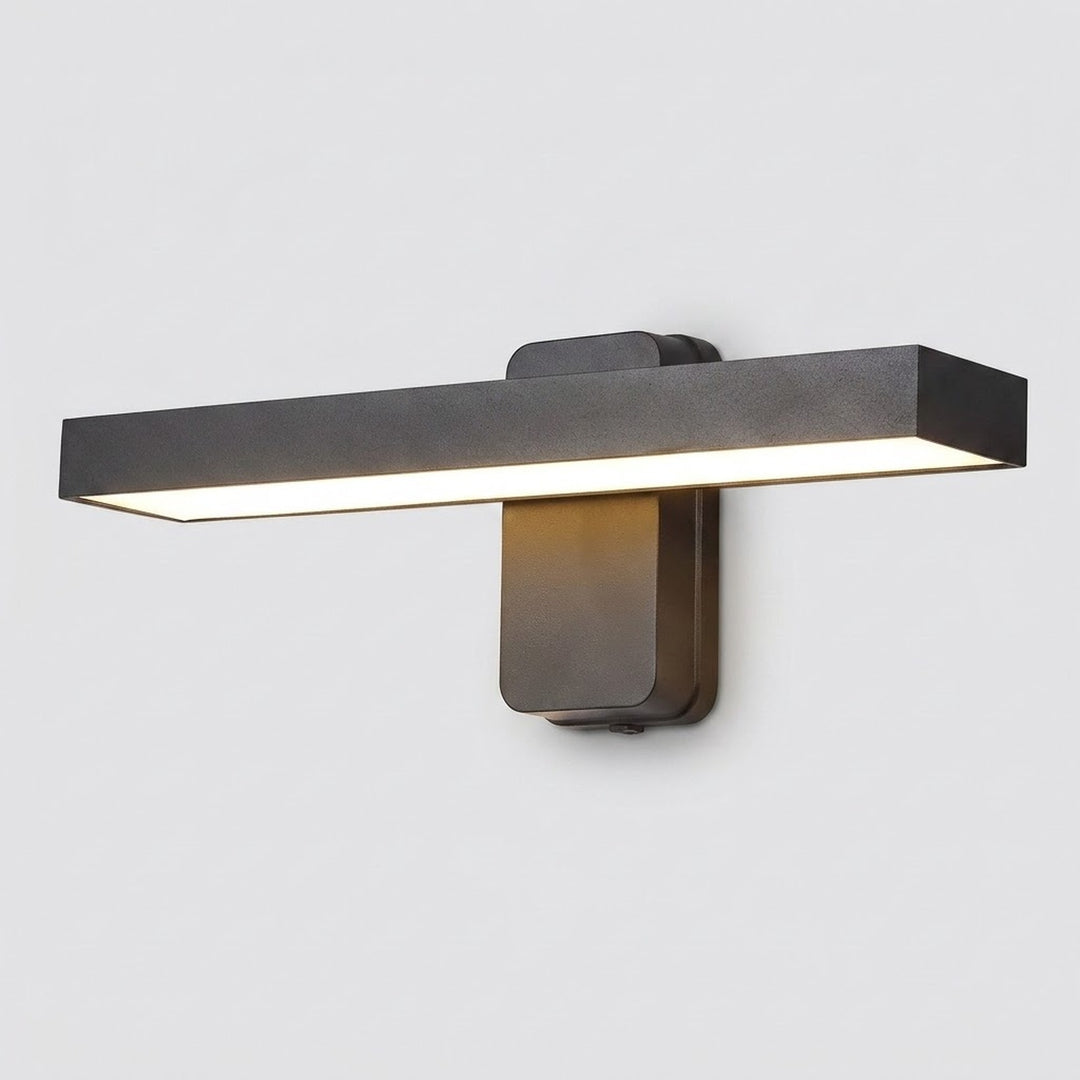 A modern horizontal rectangular wall sconce with a matte dark gray finish, emitting warm light from its underside, shown against a plain light gray background.