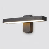 A modern horizontal rectangular wall sconce with a matte dark gray finish, emitting warm light from its underside, shown against a plain light gray background.