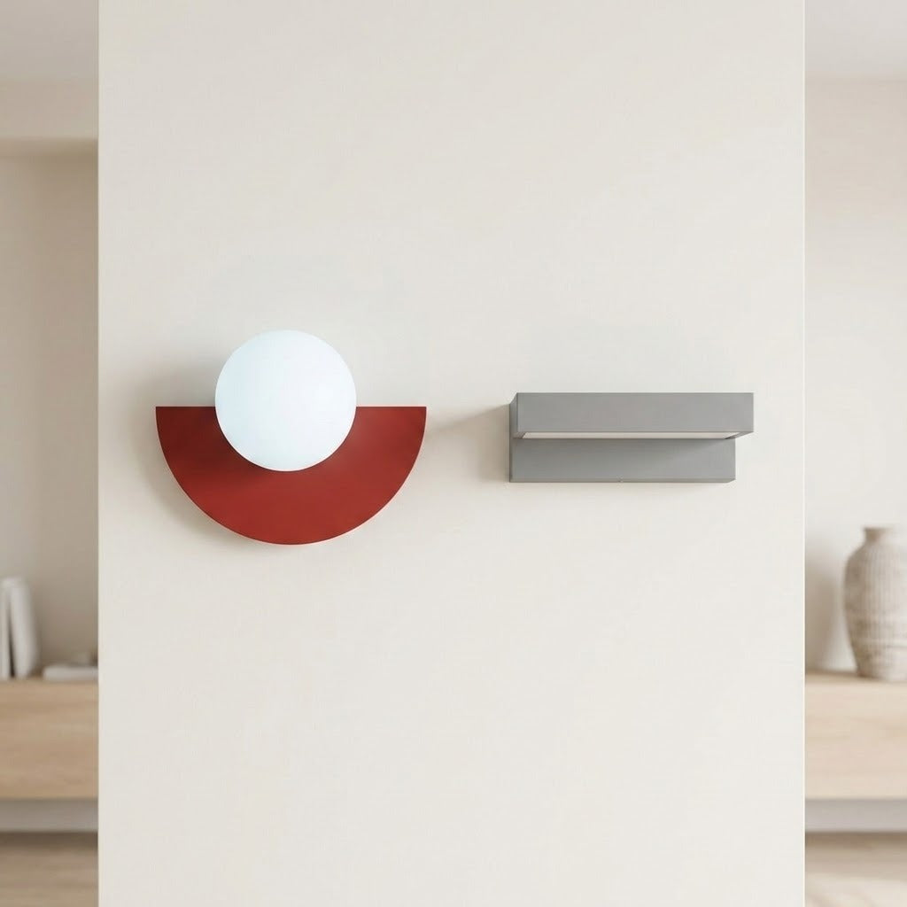 Red semicircular wall sconce with a white globe, mounted beside a gray rectangular fixture on a pale wall.