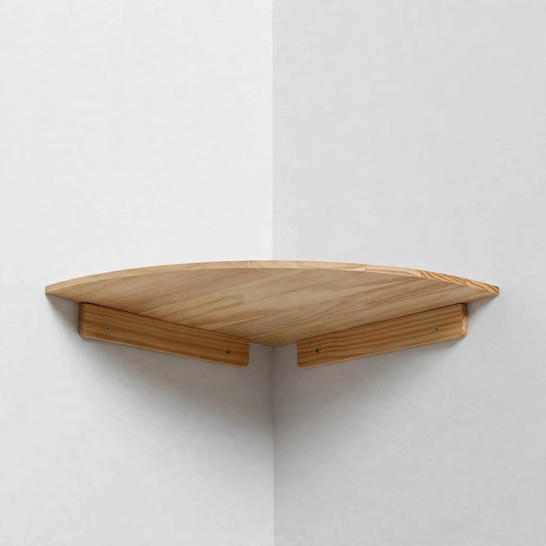 A single large light natural pine quarter-round corner shelf mounted in a white corner, viewed from below showing its underside and two wooden cleats.