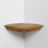 A single large light natural pine quarter-round corner shelf mounted in a white corner, viewed from below showing its underside and two wooden cleats.