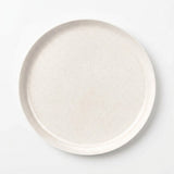 A round ceramic plate with a textured, speckled off-white finish, photographed from directly above on a clean white background.