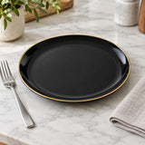 Black ceramic dinner plate beside a standard fork shows its everyday table scale.