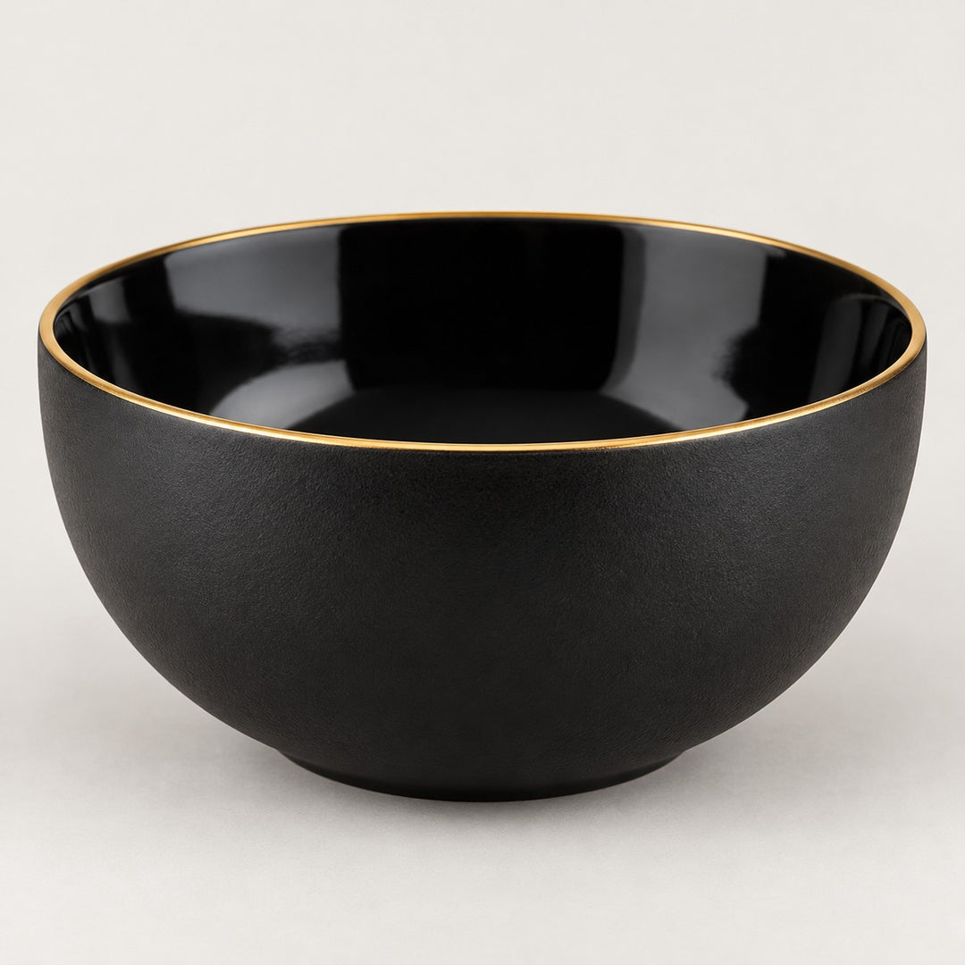 Single deep black ceramic bowl with a gold rim shown from the side on a light studio background.