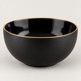 Single deep black ceramic bowl with a gold rim shown from the side on a light studio background.