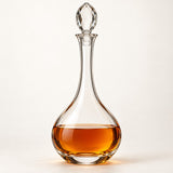 Long-Neck Teardrop glass wine decanter with amber drink on an ivory studio backdrop.