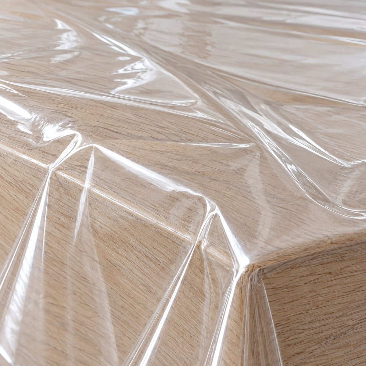 Macro view shows the smooth glossy transparent plastic and soft creases of a clear tablecloth.