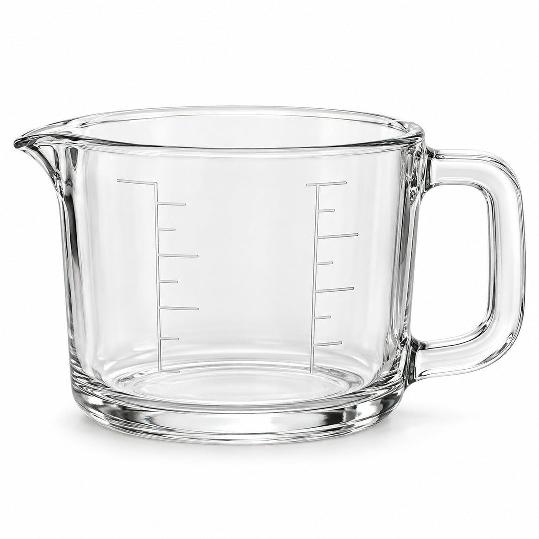 One empty clear glass 2-cup measuring cup with an integrated handle and pouring spout on white.