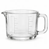 One empty clear glass 2-cup measuring cup with an integrated handle and pouring spout on white.
