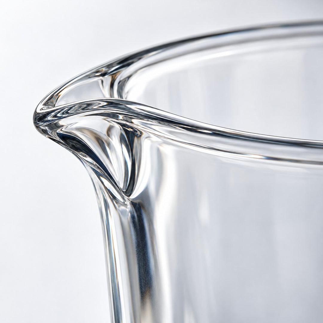 Macro view of the measuring cup's thick clear glass rim and smooth polished spout.
