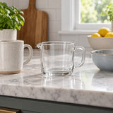 The compact 2-cup clear glass measuring cup sits beside a mug and mixing bowl for scale.