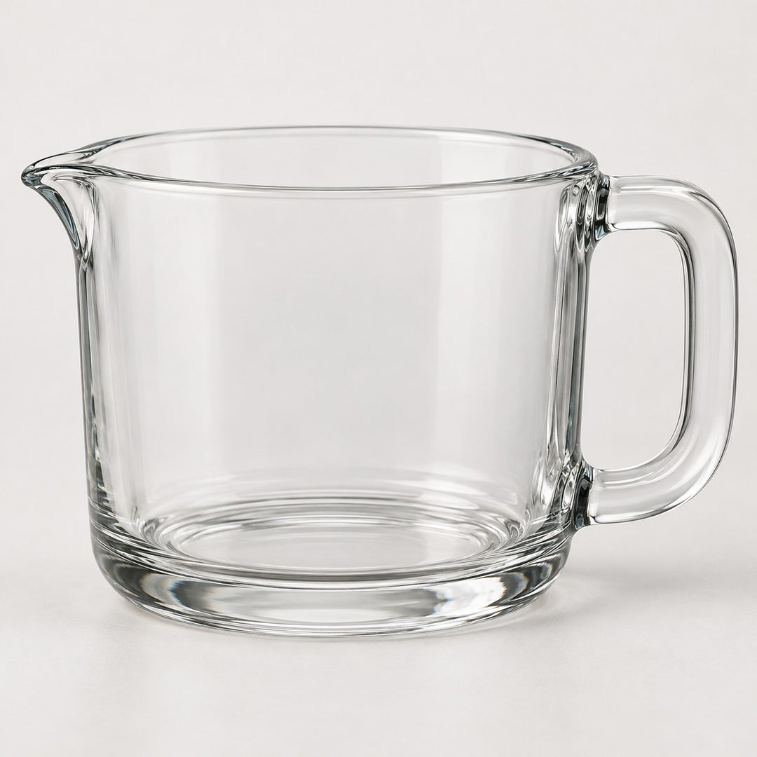 The clear glass 2-cup measuring cup stands alone against a pale neutral studio backdrop.