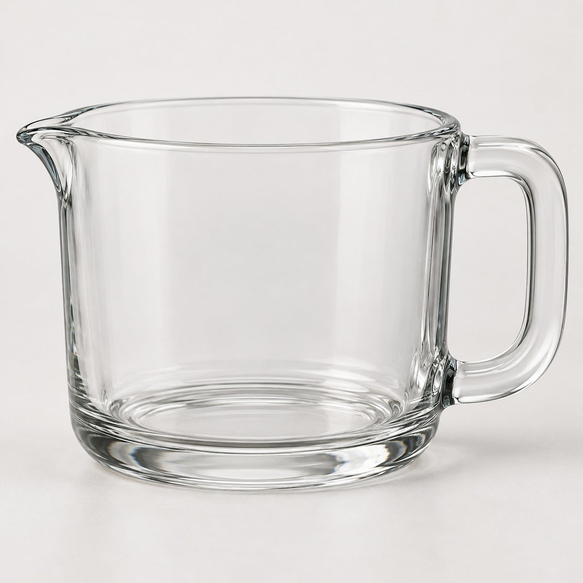 The clear glass 2-cup measuring cup stands alone against a pale neutral studio backdrop.
