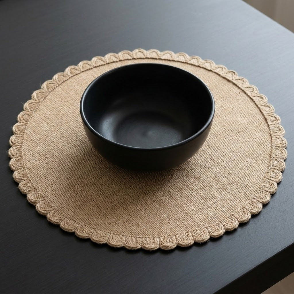A matte black ceramic bowl placed on a round beige woven placemat with a scalloped edge, set on a dark wooden table.