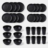 A set of matte black dinnerware, including plates, bowls, and cups, arranged neatly in rows on a light gray background.
