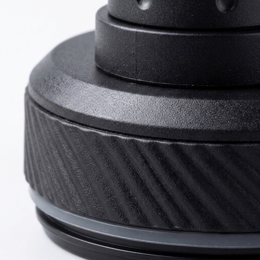Close-up of a black textured cylindrical product component with a ribbed outer band and a smooth top section on a white background.