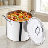 A stainless steel stockpot filled with a colorful vegetable stew and a matching lid leaning against it on a kitchen counter, with a softly blurred kitchen interior in the background.