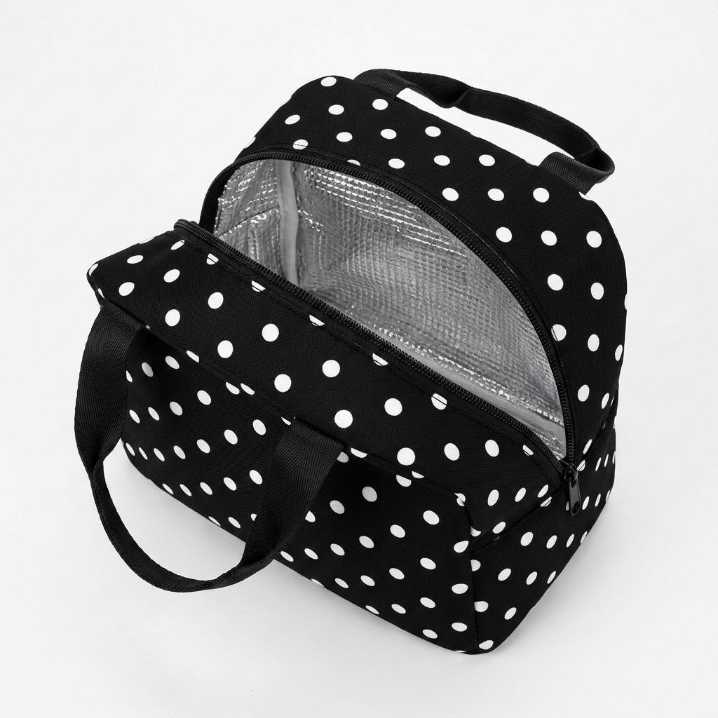 A black and white polka dot lunch bag with a silver insulated interior, shown open on a clean white background.