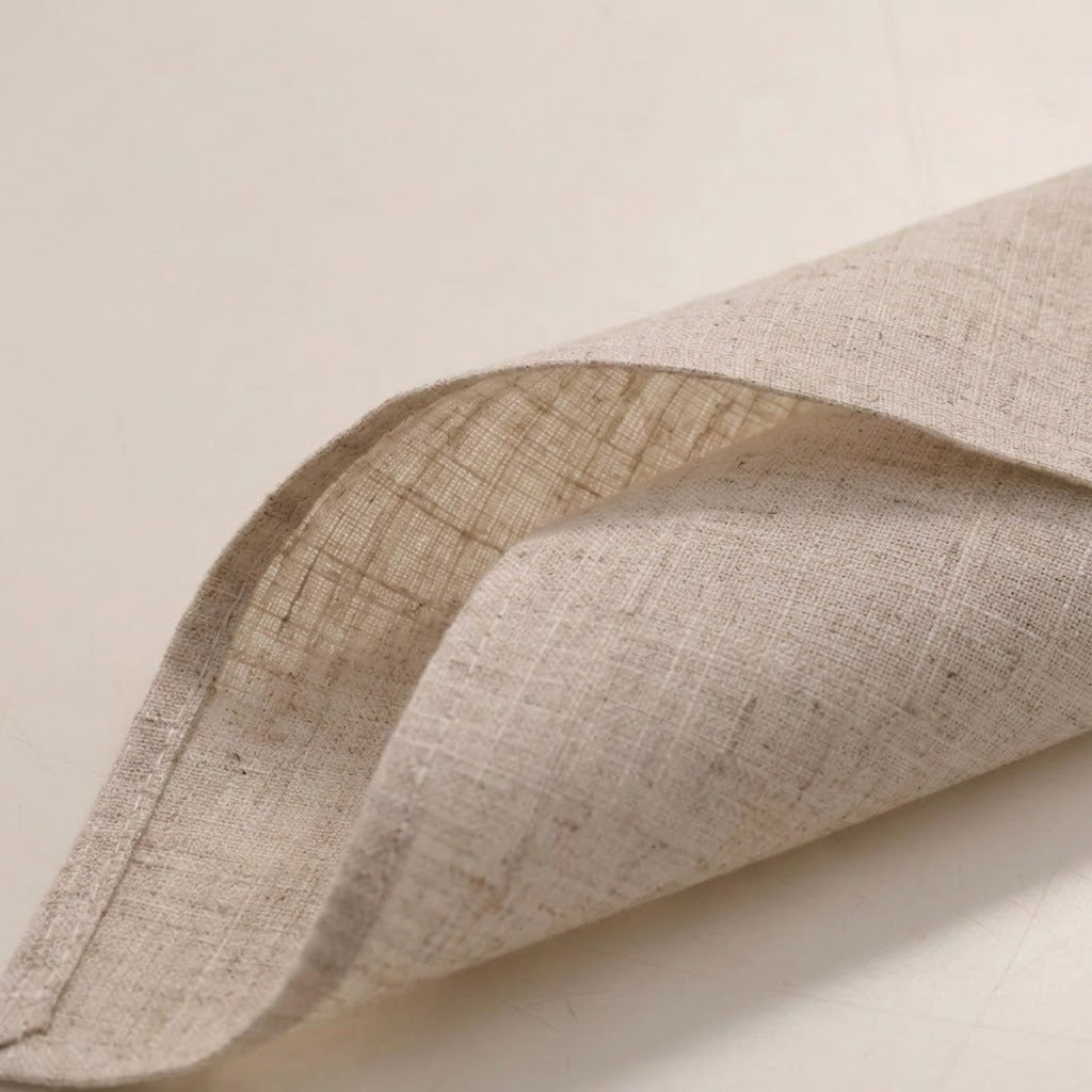 A close-up of a folded beige linen fabric napkin or cloth, showing its natural woven texture against a plain light background.