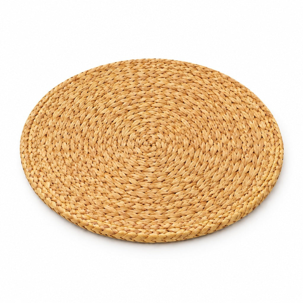 A round woven straw placemat in a natural light tan color, photographed from a top-down angle on a solid white background.