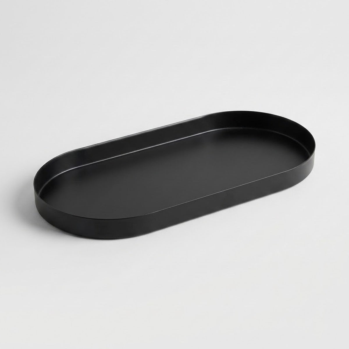 A minimalist black oval tray with a raised rim, photographed on a clean light gray background.