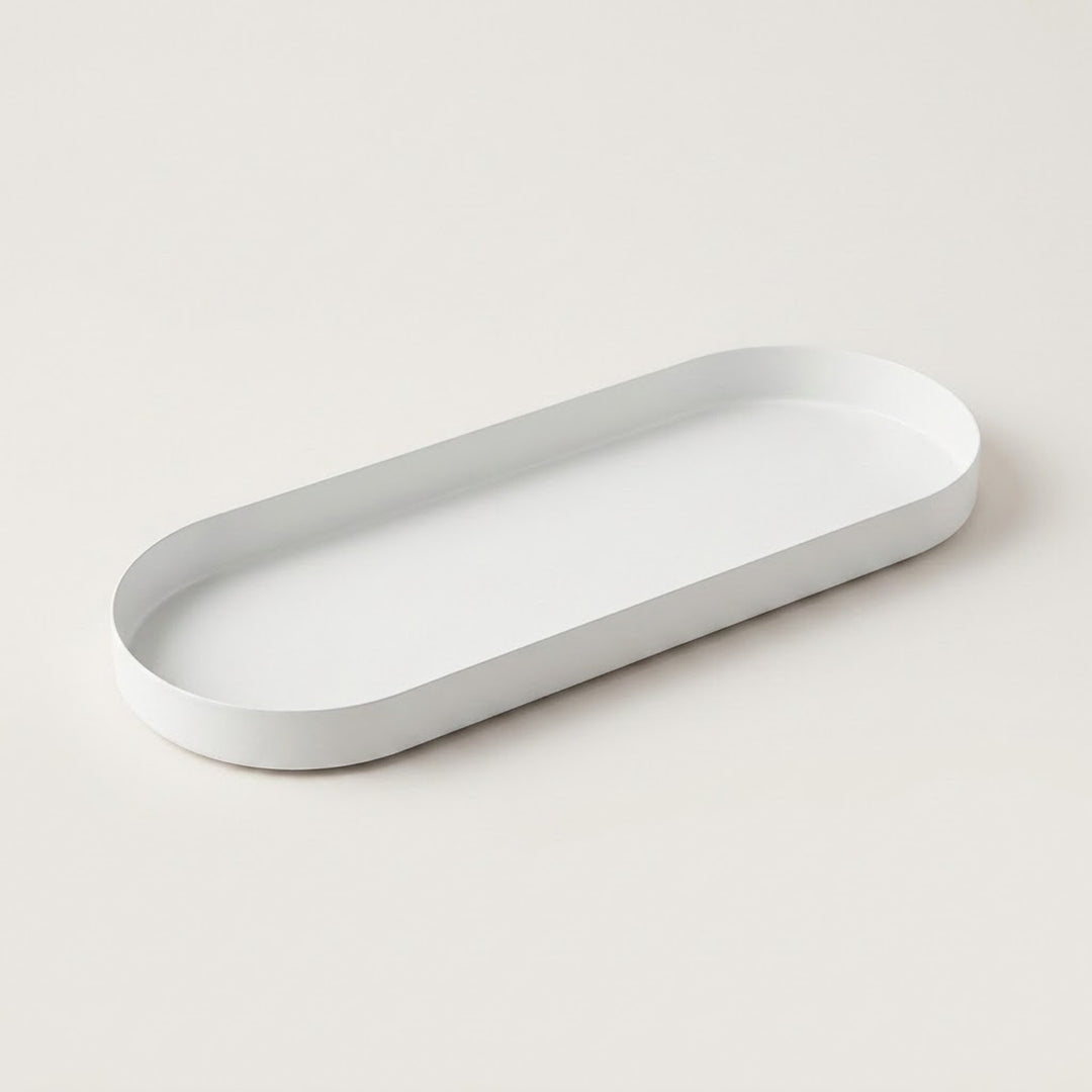 A minimalist white oval tray with rounded corners, shown from an elevated perspective on a clean, solid off-white background.