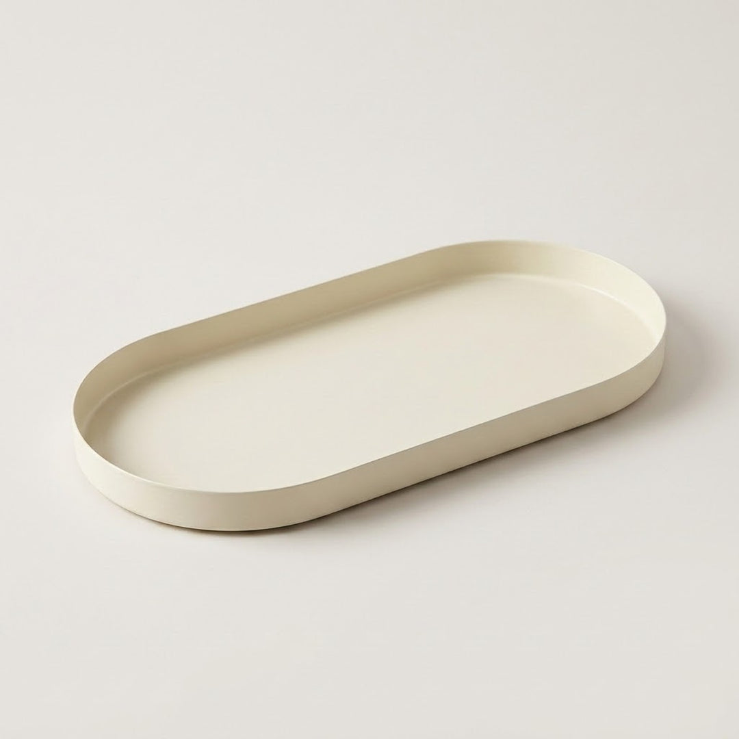 An oval tray with a low, thick rim in a warm cream or off-white color, photographed on a seamless light gray background.