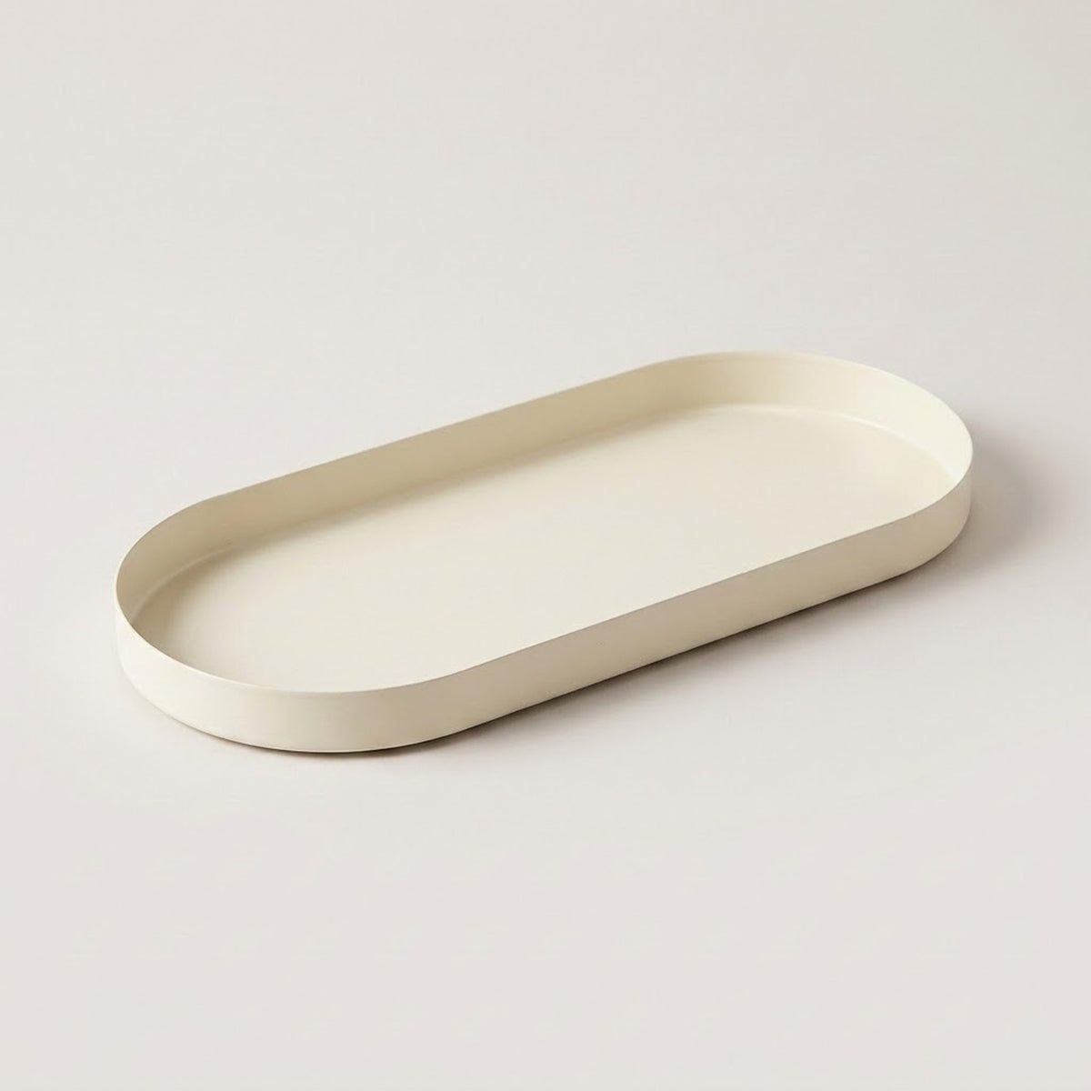 An oval tray with rounded corners in a matte cream color, photographed on a clean, light gray studio background.