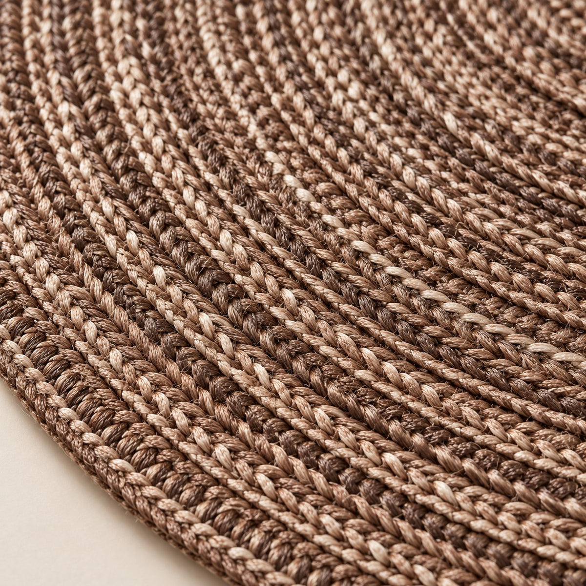 Macro detail of the brown placemat reveals its tightly braided polyester strands and ridged texture.